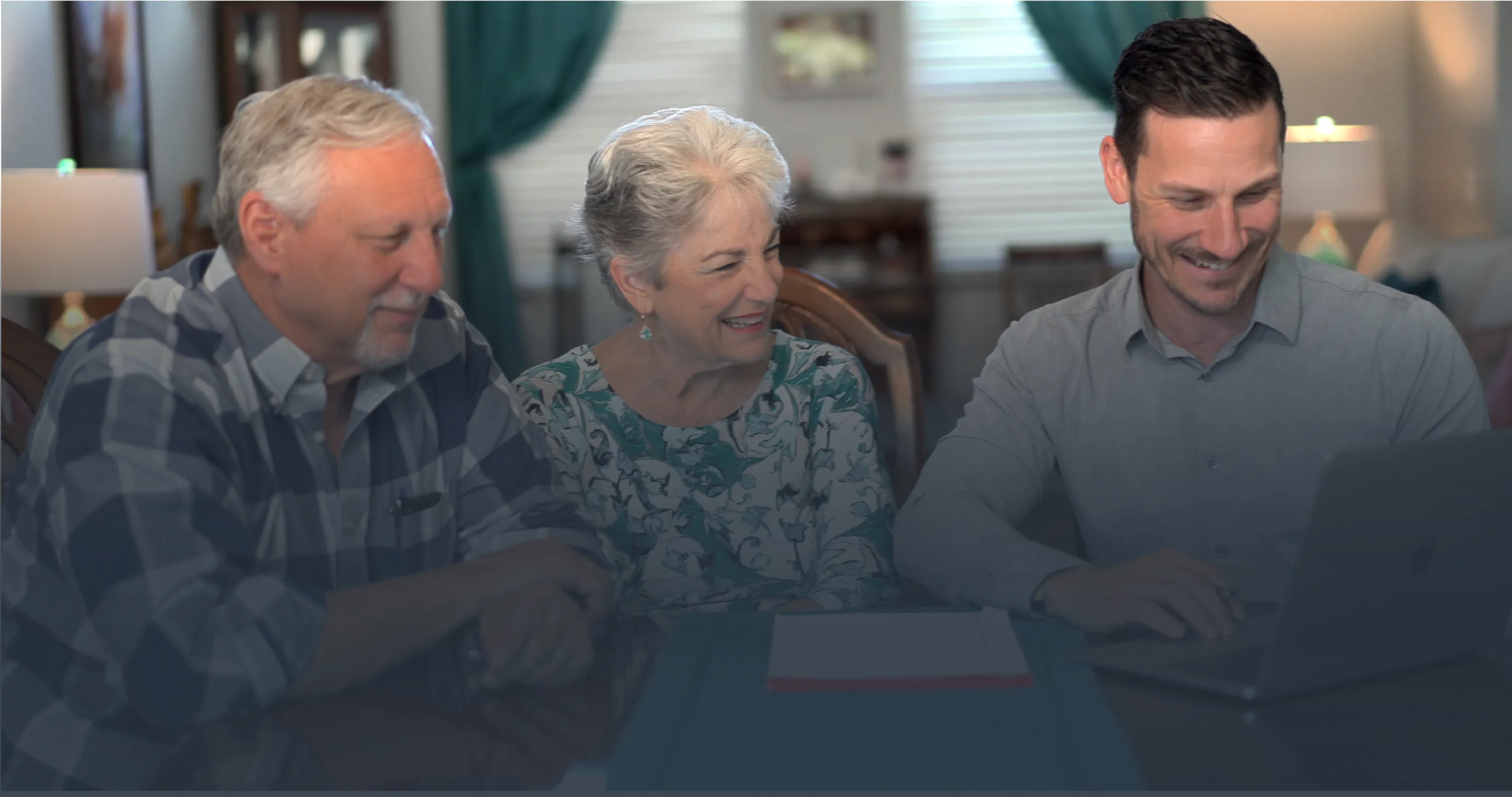 Sean Loomis sitting at a dining table with a couple, going through a plan on a laptop.